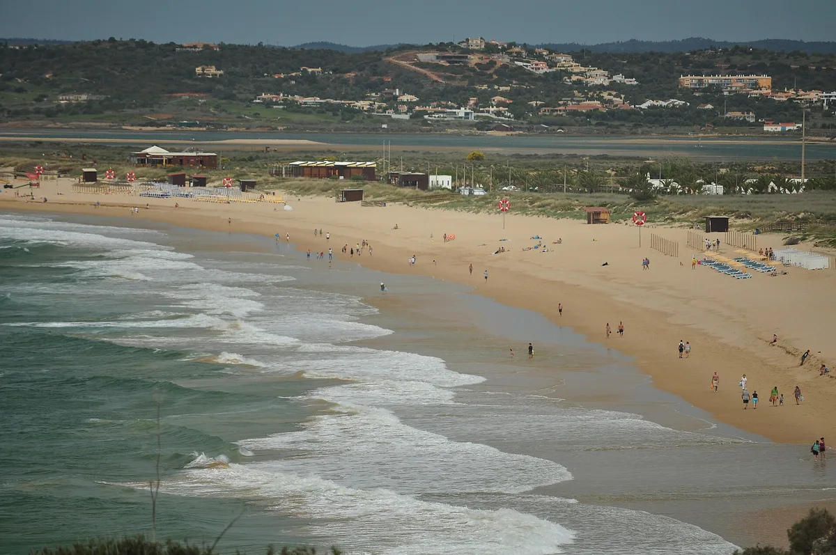 Plage d’Alvor avec la lagune et les collines de l’arrière-pays derrière les dunes