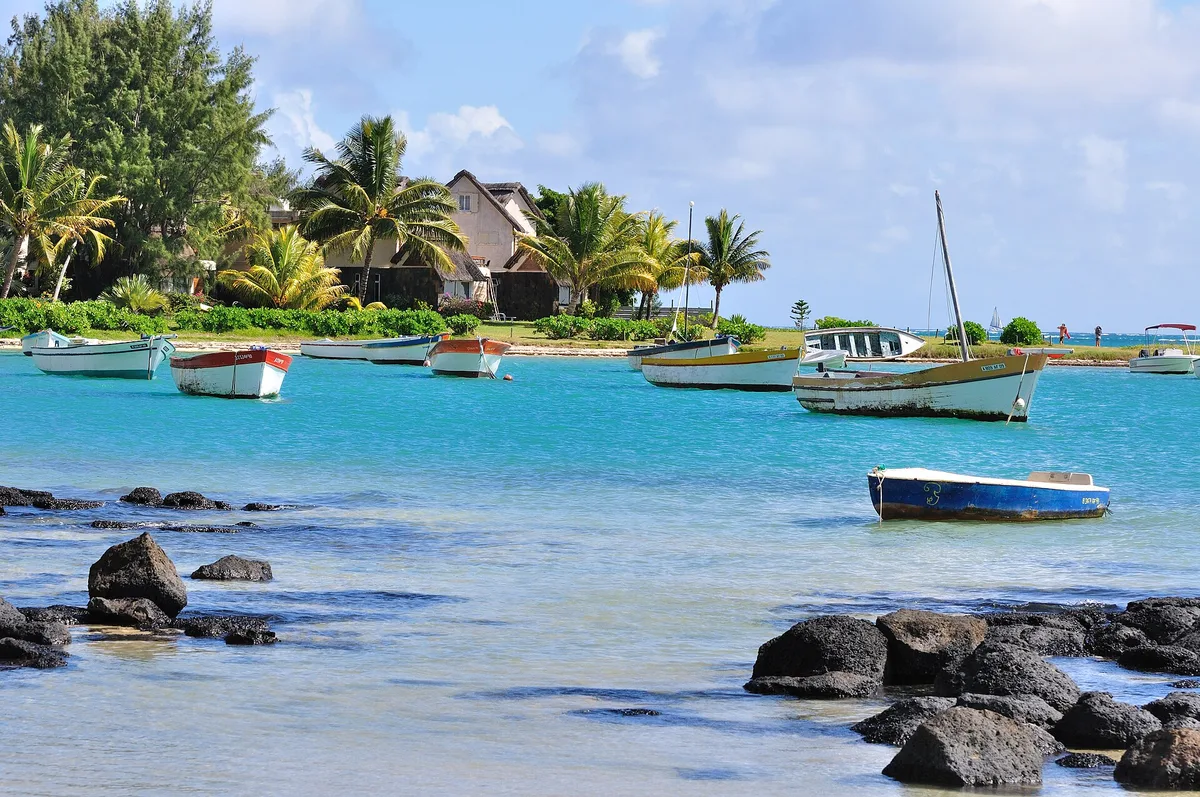 Barques de pêcheurs au mouillage dans le lagon turquoise de la côte nord, cases et cocotiers