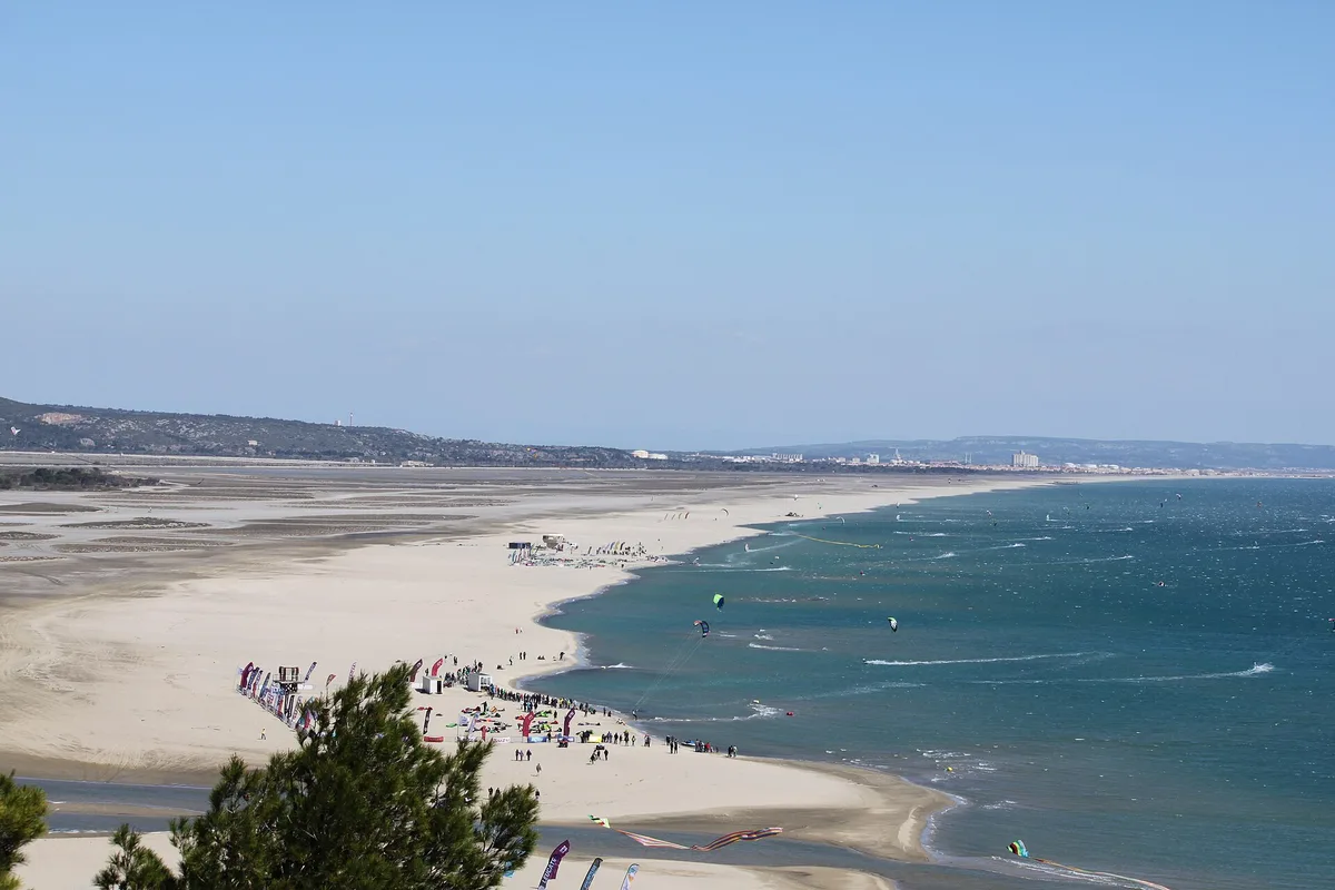 Kitesurfeurs alignés sur la plage de La Franqui pendant le Mondial du Vent, la falaise en arrière-plan