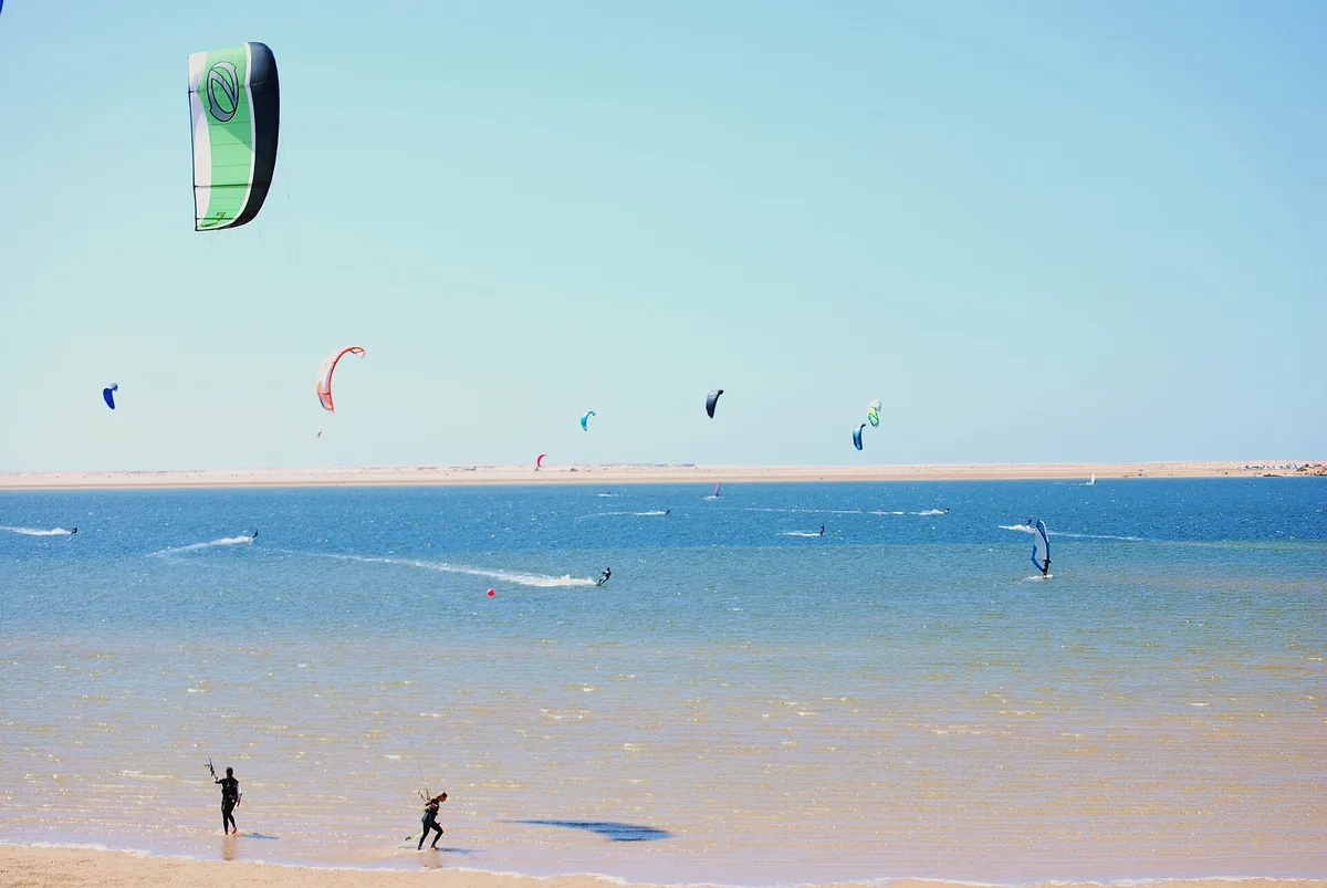 Kites et planches à voile au-dessus de la lagune de Dakhla, banc de sable au fond