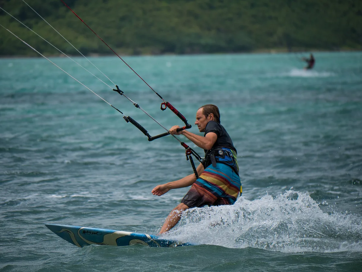 Kiteur en bord de lagon devant plusieurs ailes et des planches à voile au Morne