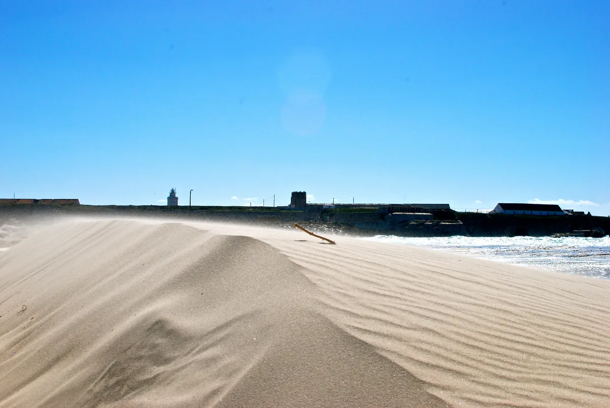 Sable soulevé par le Levante, l’île des Palomas et son phare au fond