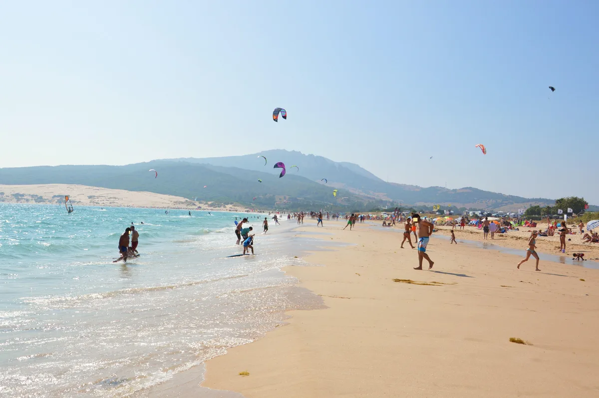 La plage de Valdevaqueros en juillet, ailes et parasols mélangés