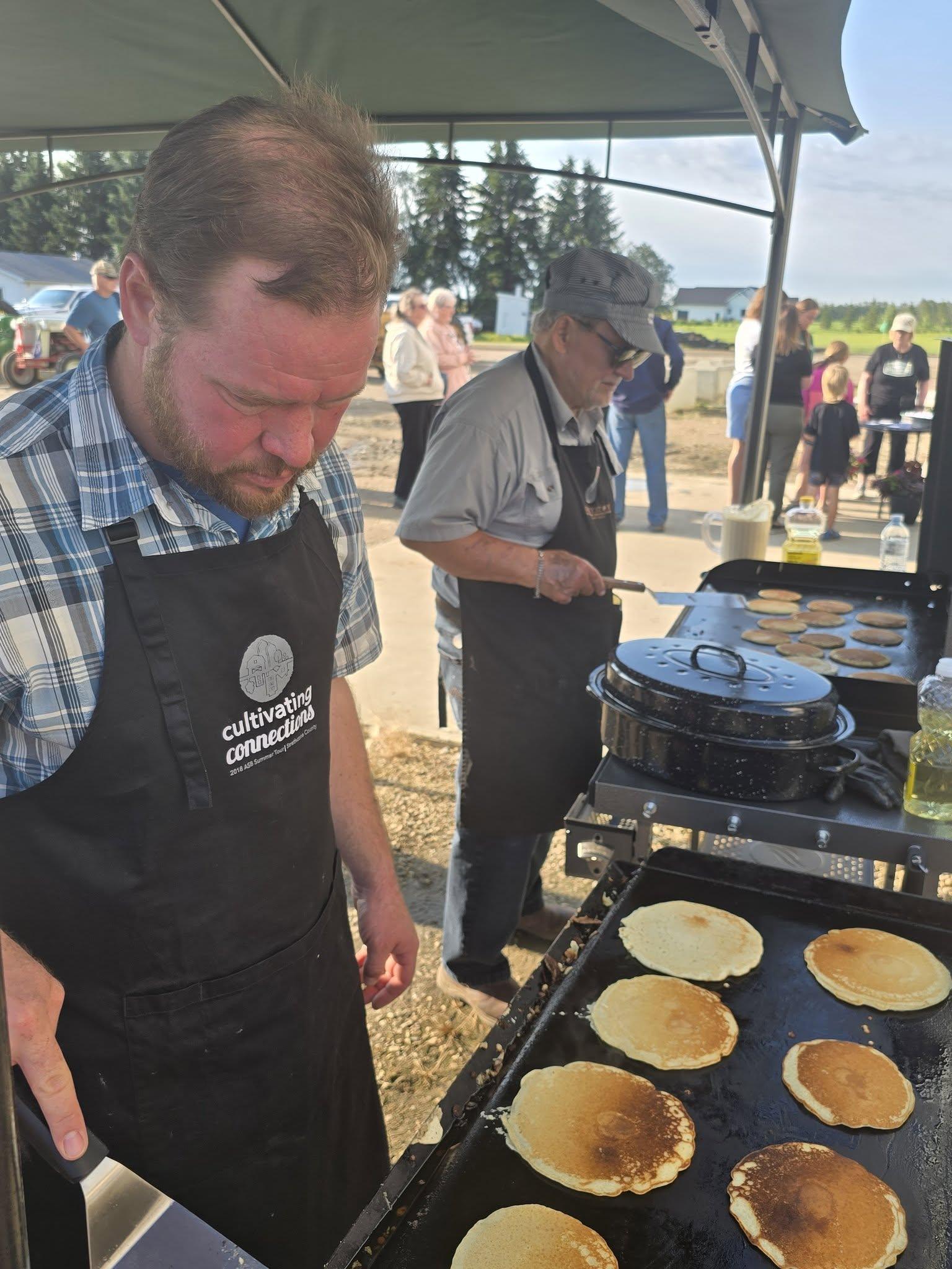 Turning pancakes on the griddle under the tent