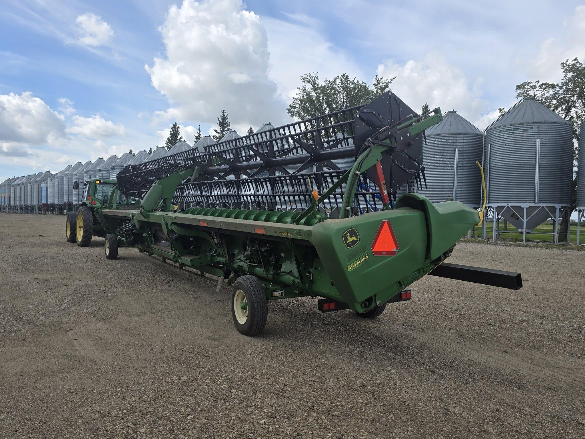 A draper header on its transport trailer under prairie cloud