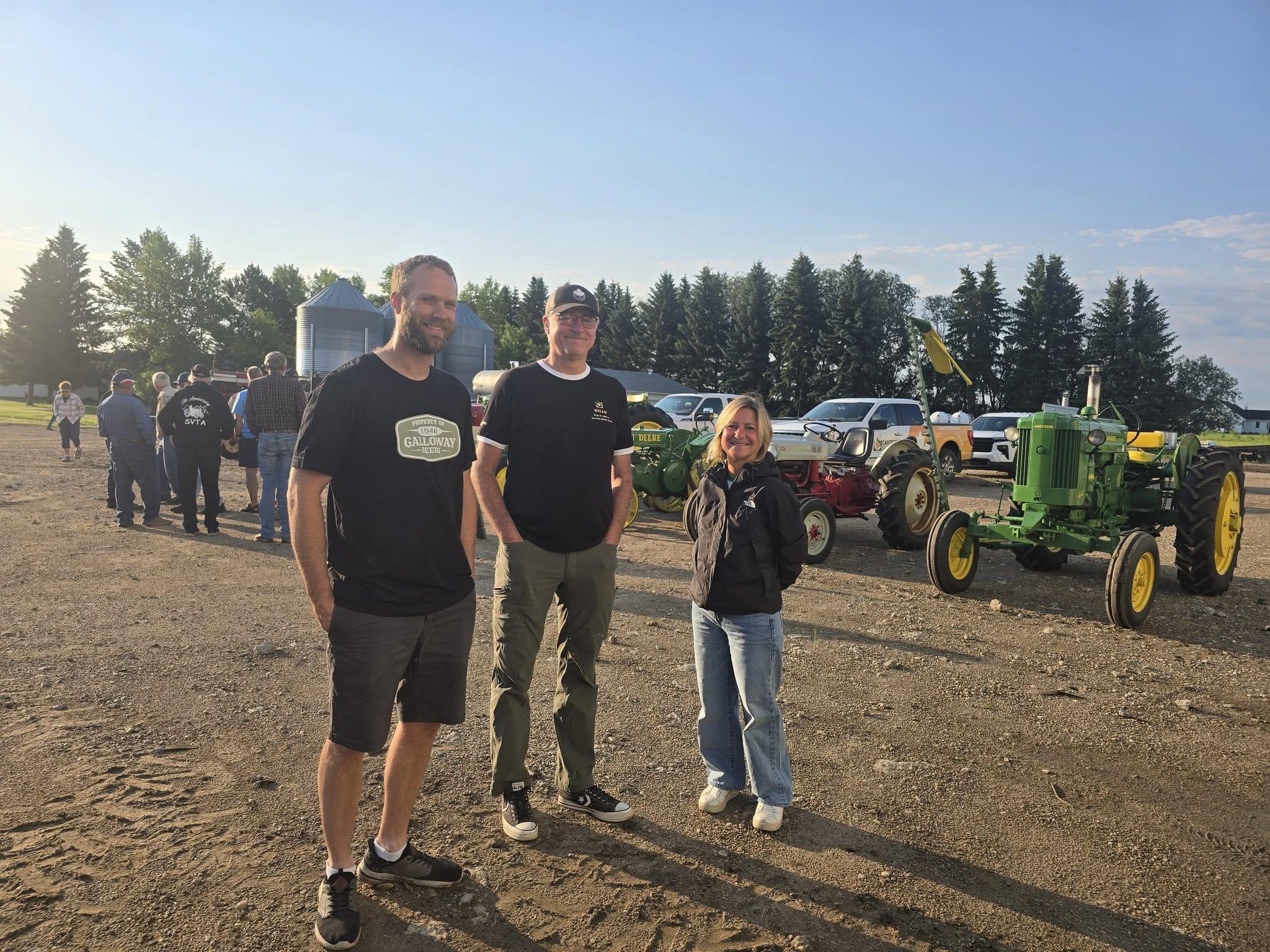 Three guests in front of the antique tractors