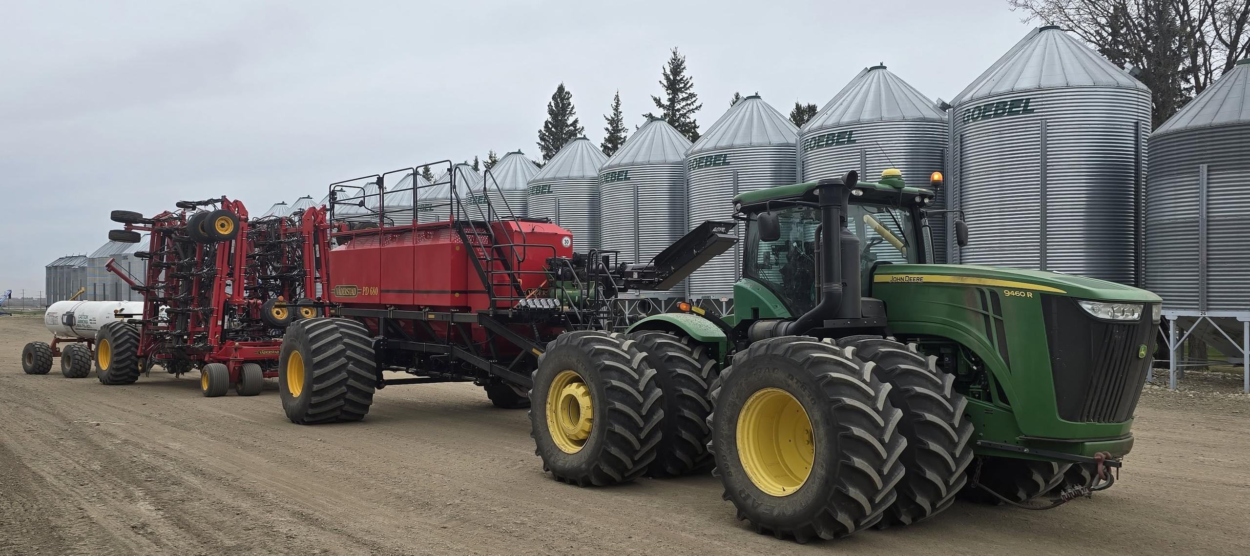 The seeding rig and tractor parked in front of the bins