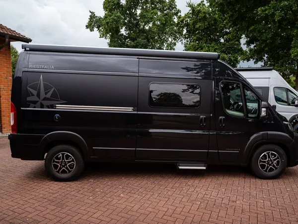 Columbus 600 D – Schwarzes Westfalia Columbus 600 D Reisemobil von der Seite geparkt.