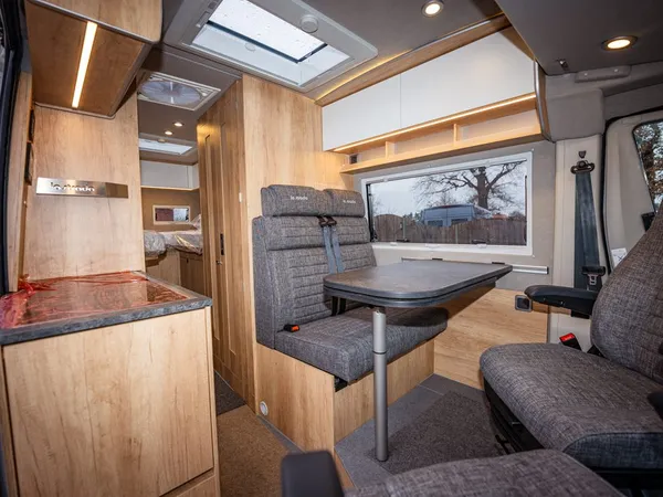 Avanti E – Gemütliche Sitzgruppe mit Tisch und Blick zum Heck im Reisemobil.