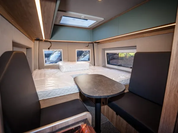 Regent E – Innenansicht des Reisemobils mit Tisch, Sitzbänken und Bettenbereich.