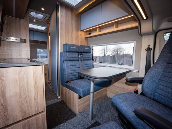 Avanti C – Reisemobil Innenraum: Gemütliche Sitzgruppe mit Tisch und drehbaren Vordersitzen.