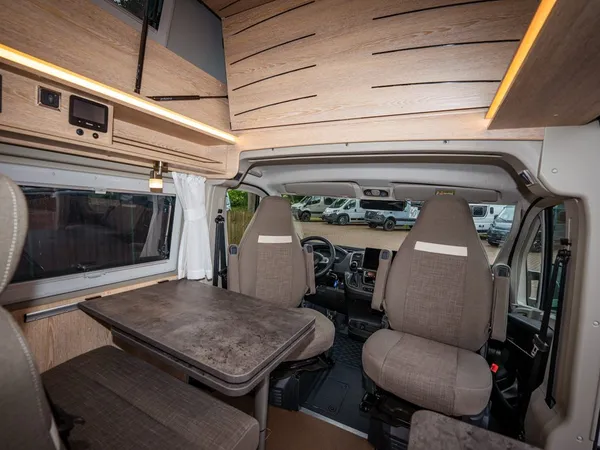 2Win Vario – Sitzgruppe und drehbare Vordersitze eines Reisemobils mit Holzinterieur.