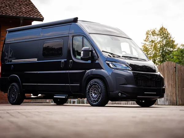 Columbus 600 D – Schwarzes Columbus 600 D Reisemobil schräg von vorne vor Gebäude.