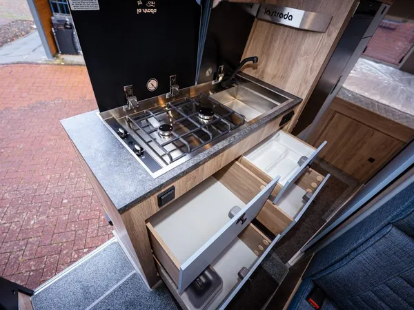 Avanti C – Moderne Wohnmobilküche mit Gaskochfeld, Spüle und offenen Schubladen.