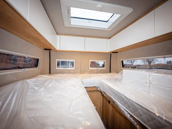 Avanti E – Bett im Wohnmobil mit Matratzen und Dachluke, obere Stauschränke.