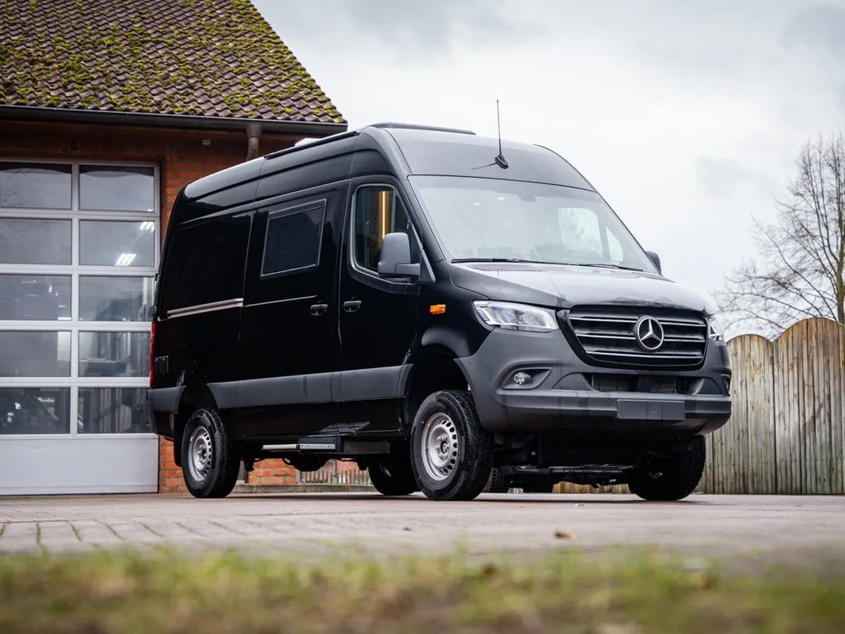 Roadstar X – Schwarzer Roadstar X Campervan, schräge Frontansicht vor einem Gebäude.