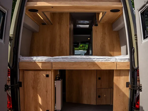 Regent S – Heckansicht des Reisemobils mit geöffneten Türen und Stauraum unter dem Bett.