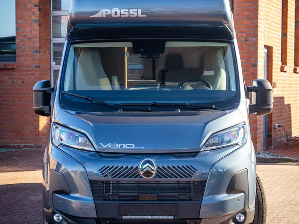 Vario 545 – Graues Pössl Vario 545 Reisemobil von vorne, vor Ziegelgebäude.