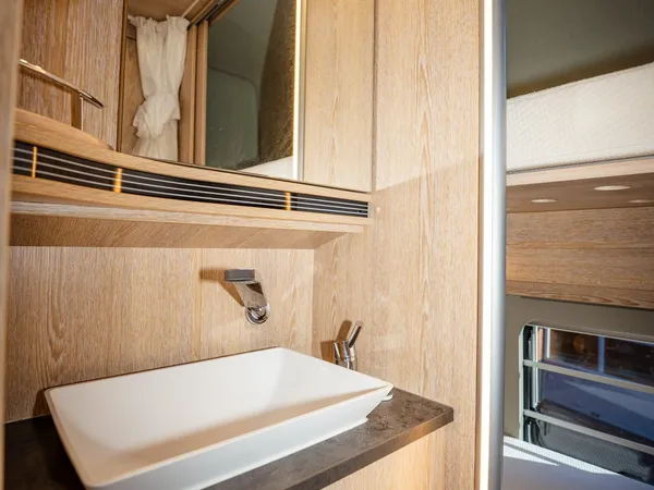Vario 545 – Modernes Badezimmer mit Waschtisch, Spiegel und Holzverkleidung im Reisemobil.
