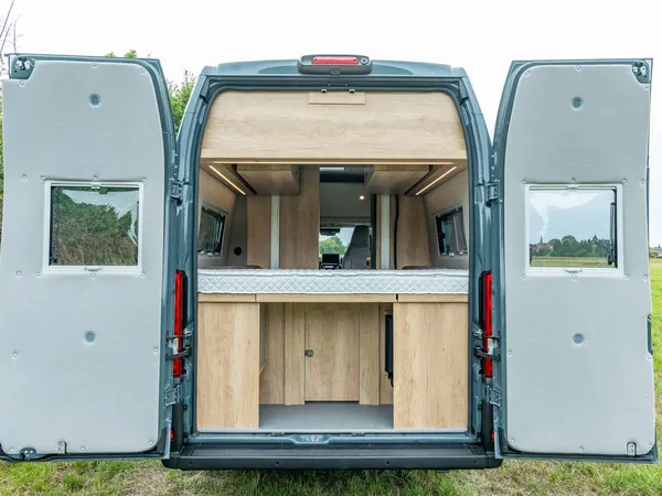Avanti R – Heckansicht eines Reisemobils mit offener Tür, zeigt Bett und Stauraum.