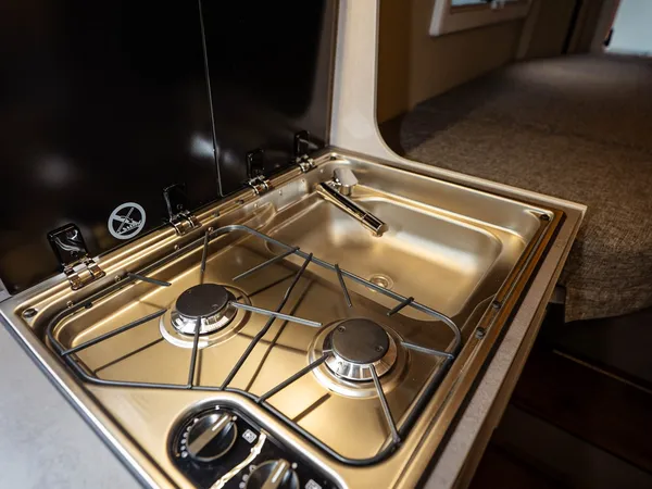 Summit Shine 600 L – Kochfeld und Spüle in der Wohnmobilküche, mit Bett im Hintergrund.