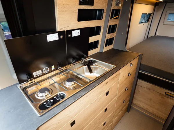 Roadstar XL Evo – Moderne Wohnmobilküche mit Kochfeld, Spüle, Holzschränken und LED-Beleuchtung.
