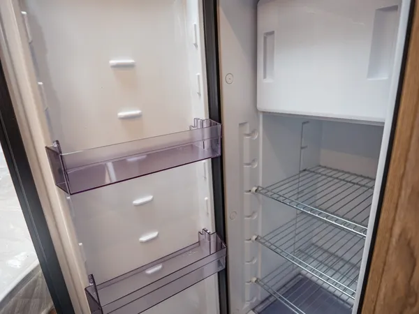 Regent EB – Offener Kühlschrank eines Reisemobils mit leeren Fächern und Ablagen.