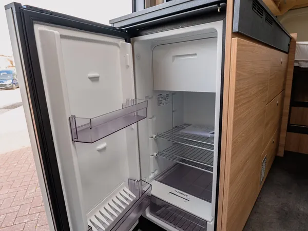 Trenta 640 – Kühlschrank im Reisemobil mit offener Tür und hellem Holzinterieur.