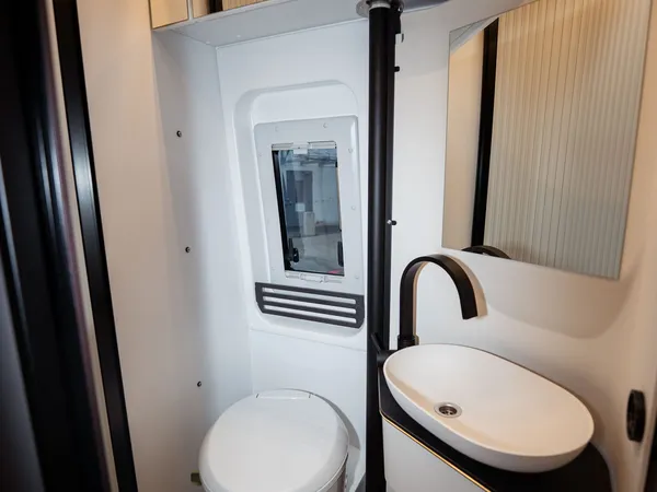 Roadstar XL Evo – Modernes Badezimmer in einem Reisemobil mit Toilette, Waschbecken und Dachluke.
