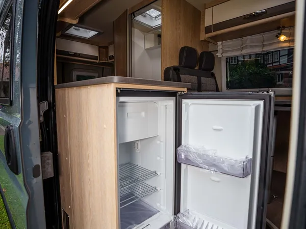 Summit 600 B – Kühlschrank im Reisemobil mit offener Schiebetür und Blick nach draußen.