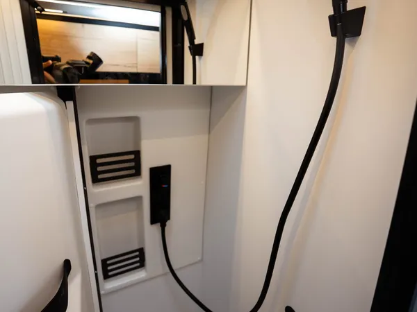 Roadstar XL Evo – Moderne Duschkabine in einem Reisemobil mit schwarzem Duschkopf und Ablagen.