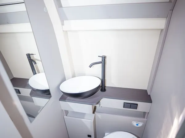 Nansen 600L – Modernes Bad im Wohnmobil mit Toilette, Waschbecken und Spiegel.