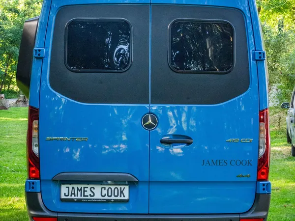 James Cook 600 D – Blauer James Cook 600 D Reisemobil, Heckansicht auf grüner Wiese.