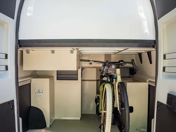 Columbus Liner – Heckstauraum mit Fahrrad im Reisemobil und geöffneten Hecktüren.