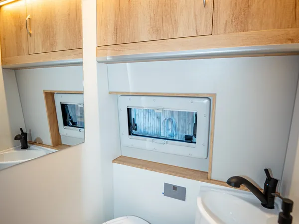 Avanti EB – Modernes Bad mit Toilette, Waschbecken und Holzschränken in einem Reisemobil.