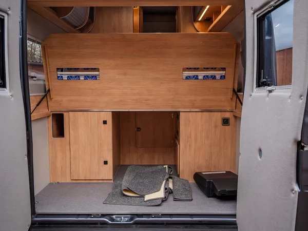 Avanti F – Heckstauraum eines Reisemobils mit geöffneten Türen und ausgebautem Bett.