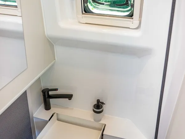 Columbus Liner – Badezimmer mit Fenster, schwarzer Armatur und ausklappbarem Waschbecken.