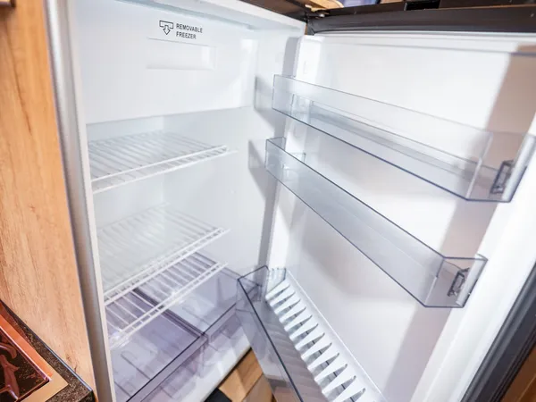 Avanti EB – Offener Kühlschrank im Reisemobil mit leeren Fächern und Ablagen.