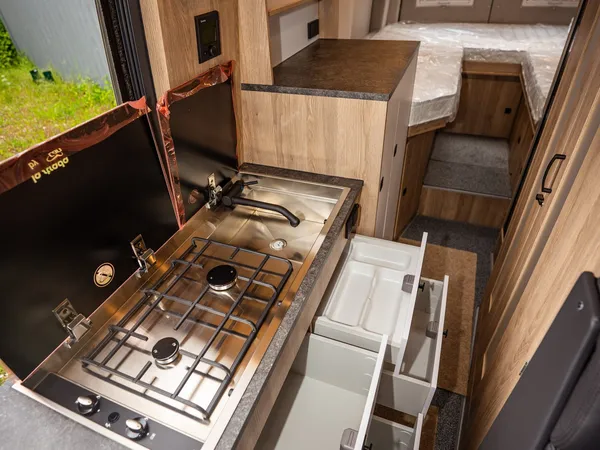 Regent EB – Blick durch das Reisemobil mit Küche, geöffneten Schubladen und Bett