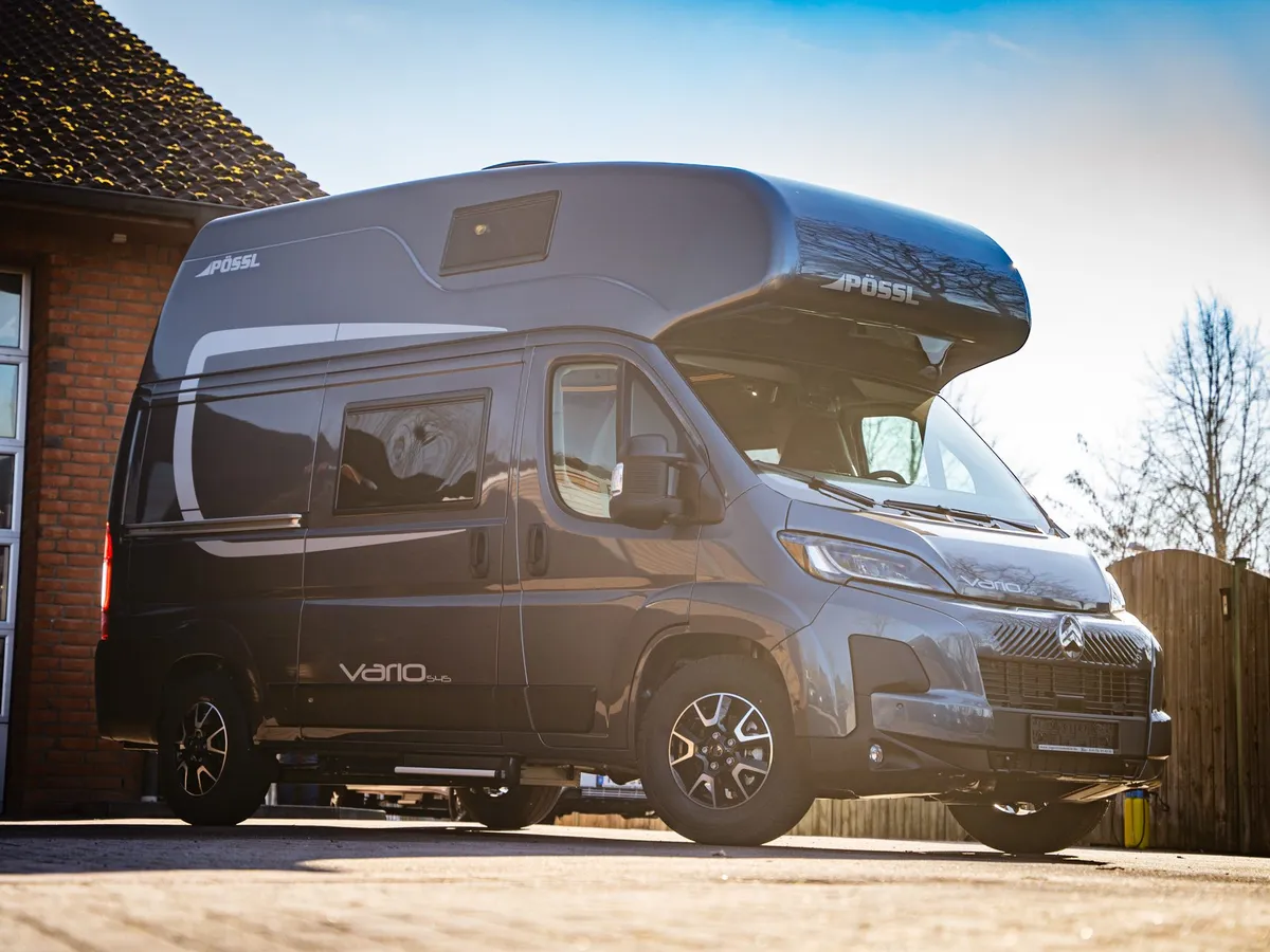 Vario 545 – Grauer Pössl Vario 545 Kastenwagen schräg von vorne vor Gebäude.