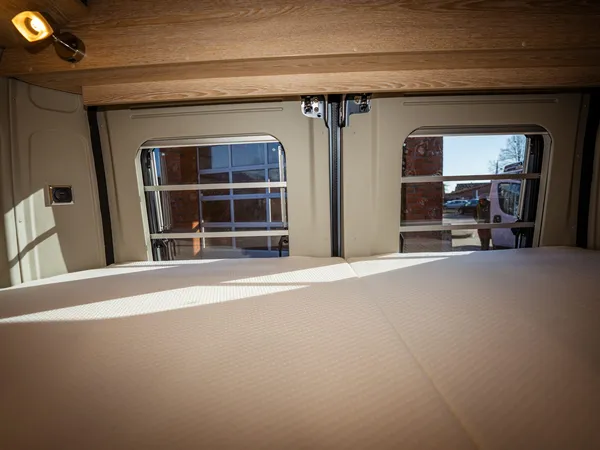 Vario 545 – Bett im Vario 545 mit Blick durch die Hecktüren nach draußen.