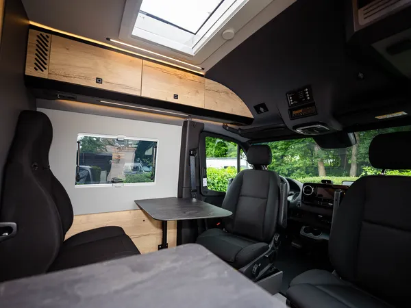 Roadstar XL Evo – Moderne Sitzgruppe und Cockpit des Reisemobils mit Tisch und Stühlen.