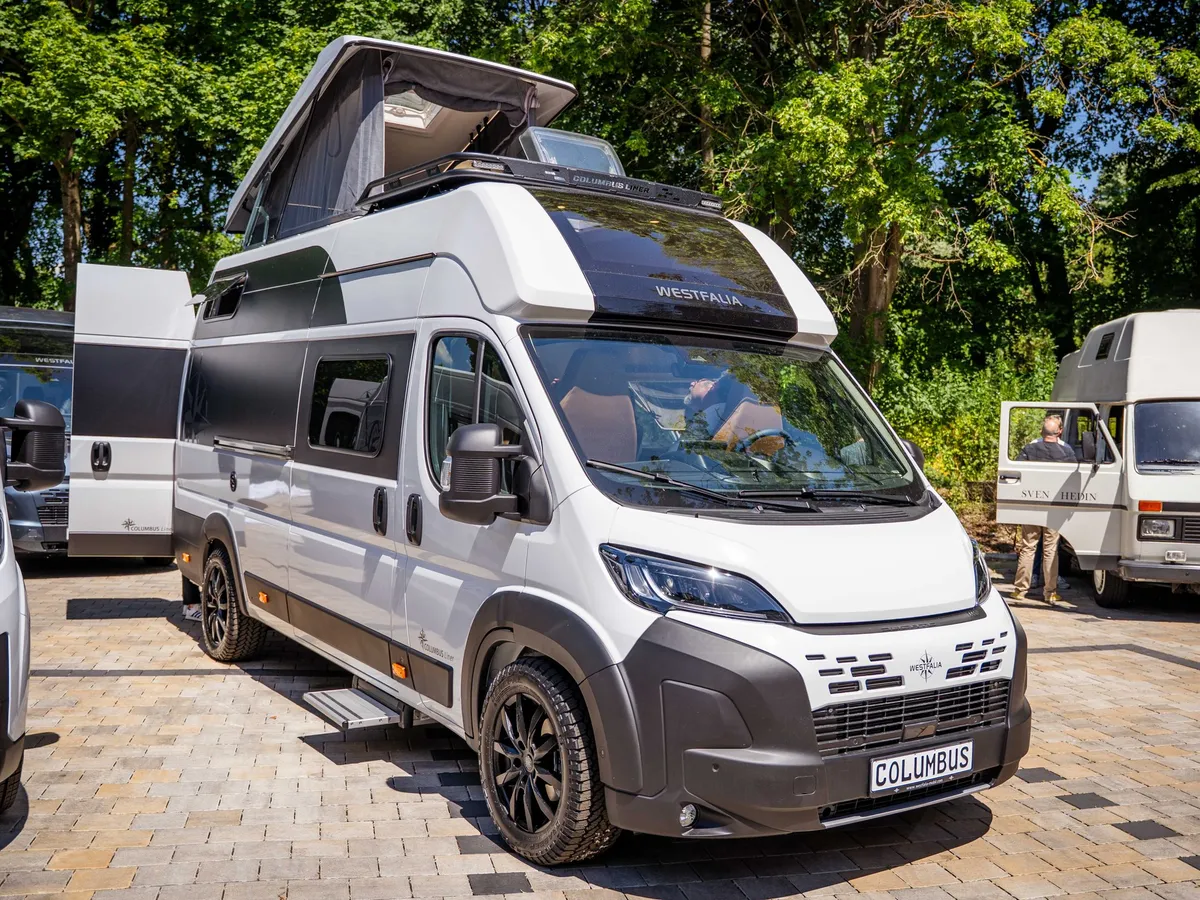 Columbus Liner – Weißer Westfalia Columbus Camper mit geöffnetem Aufstelldach, schräg von vorne.