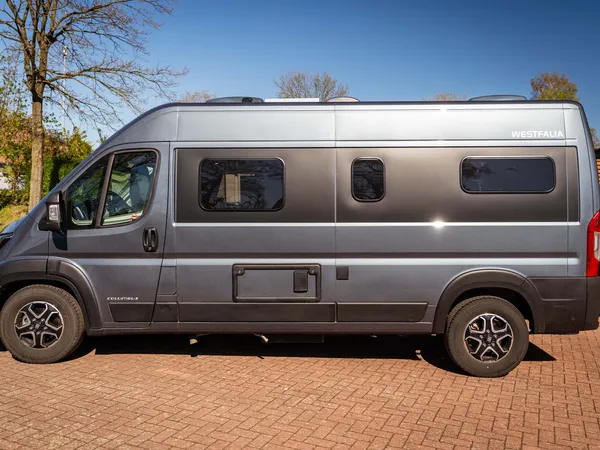 Columbus 600 E – Graues Reisemobil (Columbus 600 E) von der Seite auf Pflastersteinen.