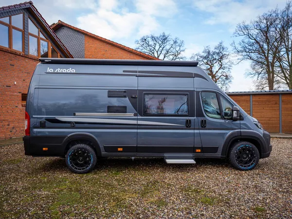 Avanti F – Graues La Strada Avanti F Reisemobil seitlich vor Haus und Bäumen.
