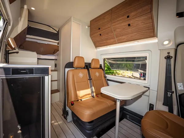 Columbus Liner – Innenansicht mit Sitzgruppe, Tisch, Kühlschrank und Bettenbereich.