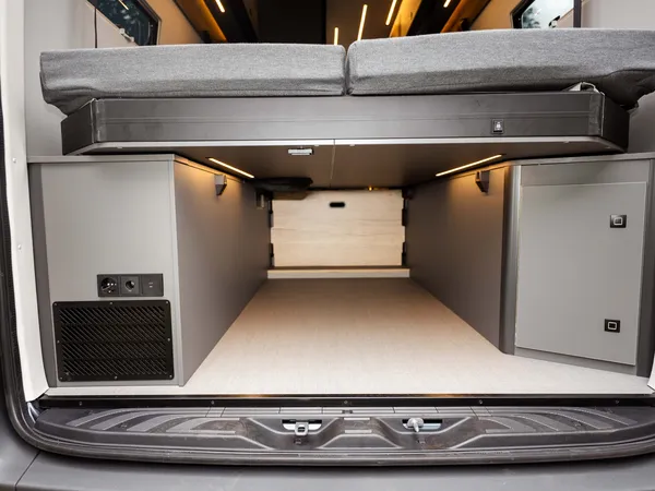 Roadstar XL Evo – Heckstauraum mit hochgeklapptem Bett und integrierten Schränken im Reisemobil.