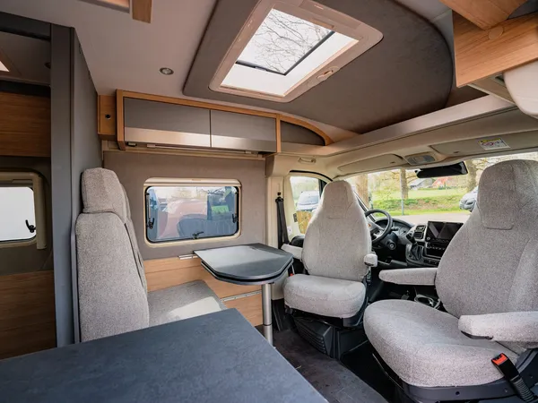 Trenta 640 – Sitzgruppe und Cockpitbereich in einem Reisemobil mit hellem Stoffbezug.