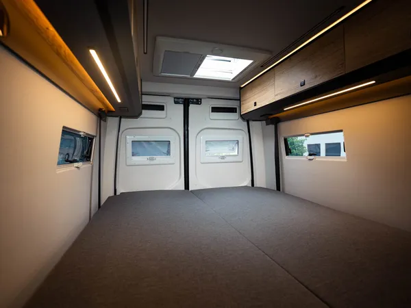 Roadstar XL Evo – Großes Doppelbett im Heckbereich eines Reisemobils mit Dachfenster und Schränken.