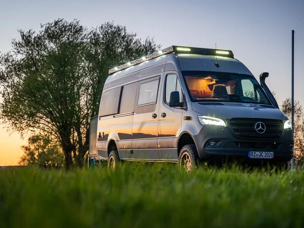 Regent EB – Graues Reisemobil (Regent EB) von schräg vorne im Abendlicht auf Wiese.
